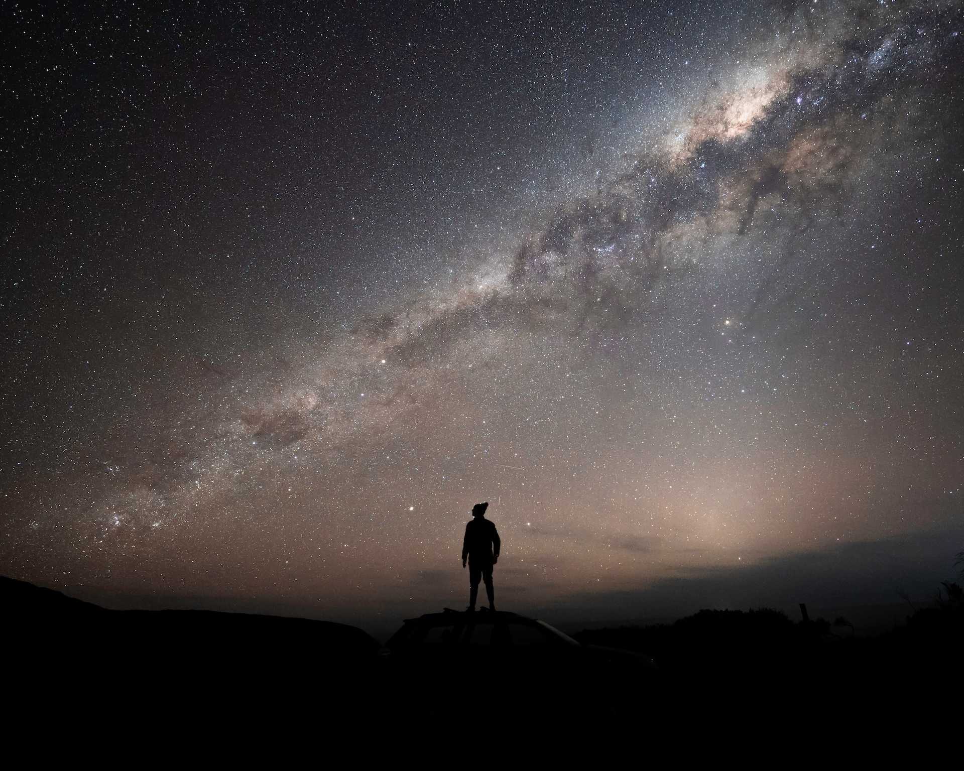 A man gazing into the night sky illuminated by the starts